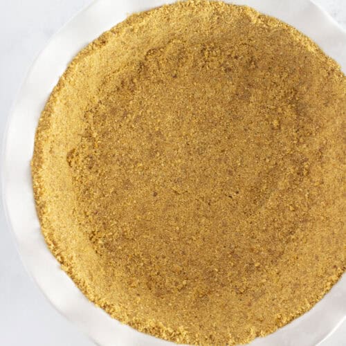 A homemade graham cracker crust in a white pie plate.