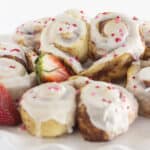 Heart shaped cinnamon rolls on a white cake plate.