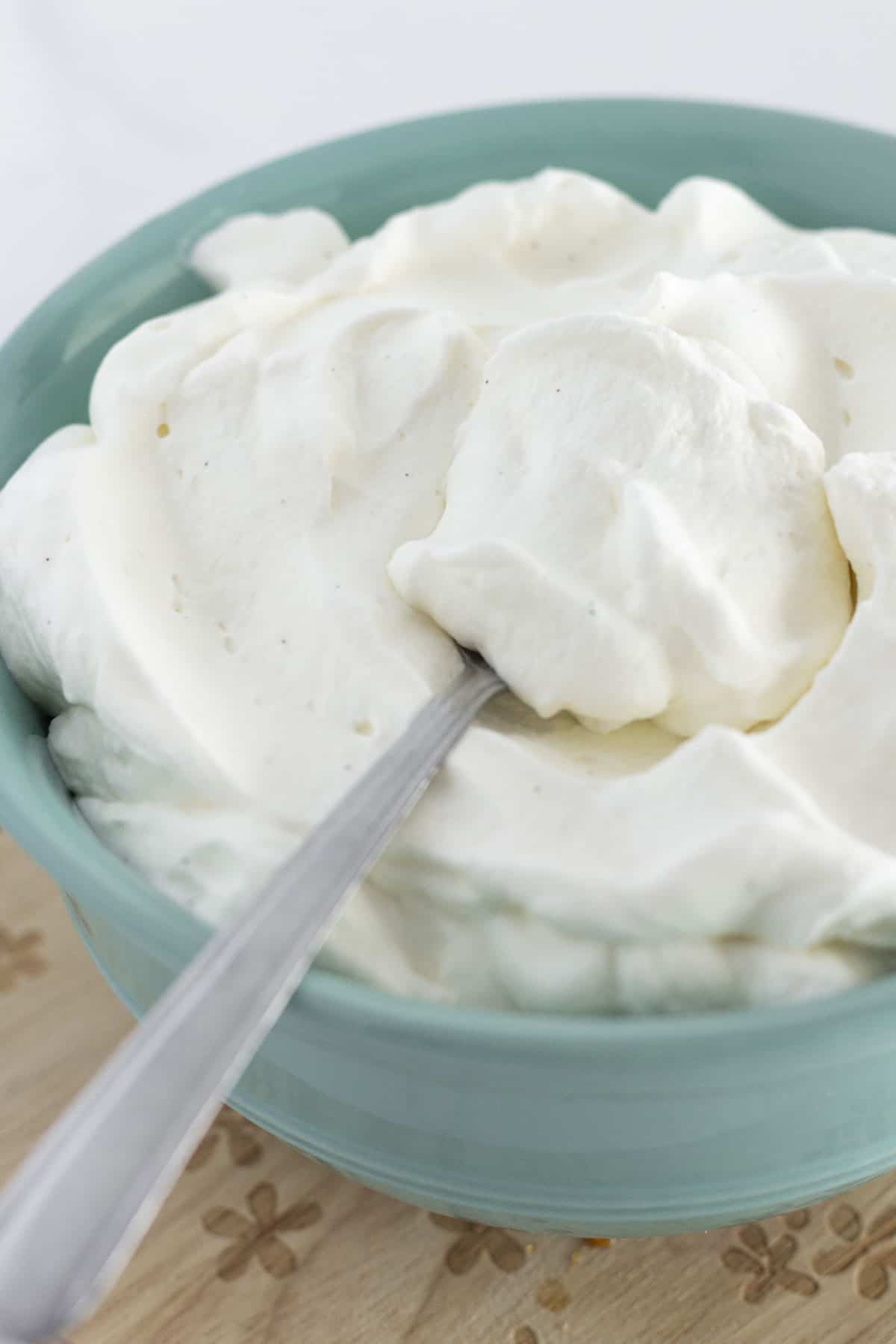 Fresh made whipped cream in a bowl with a spoon for serving.