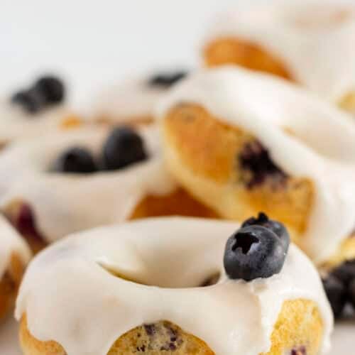 Blueberry Cake Donuts ready to serve with fresh blueberries and glaze.