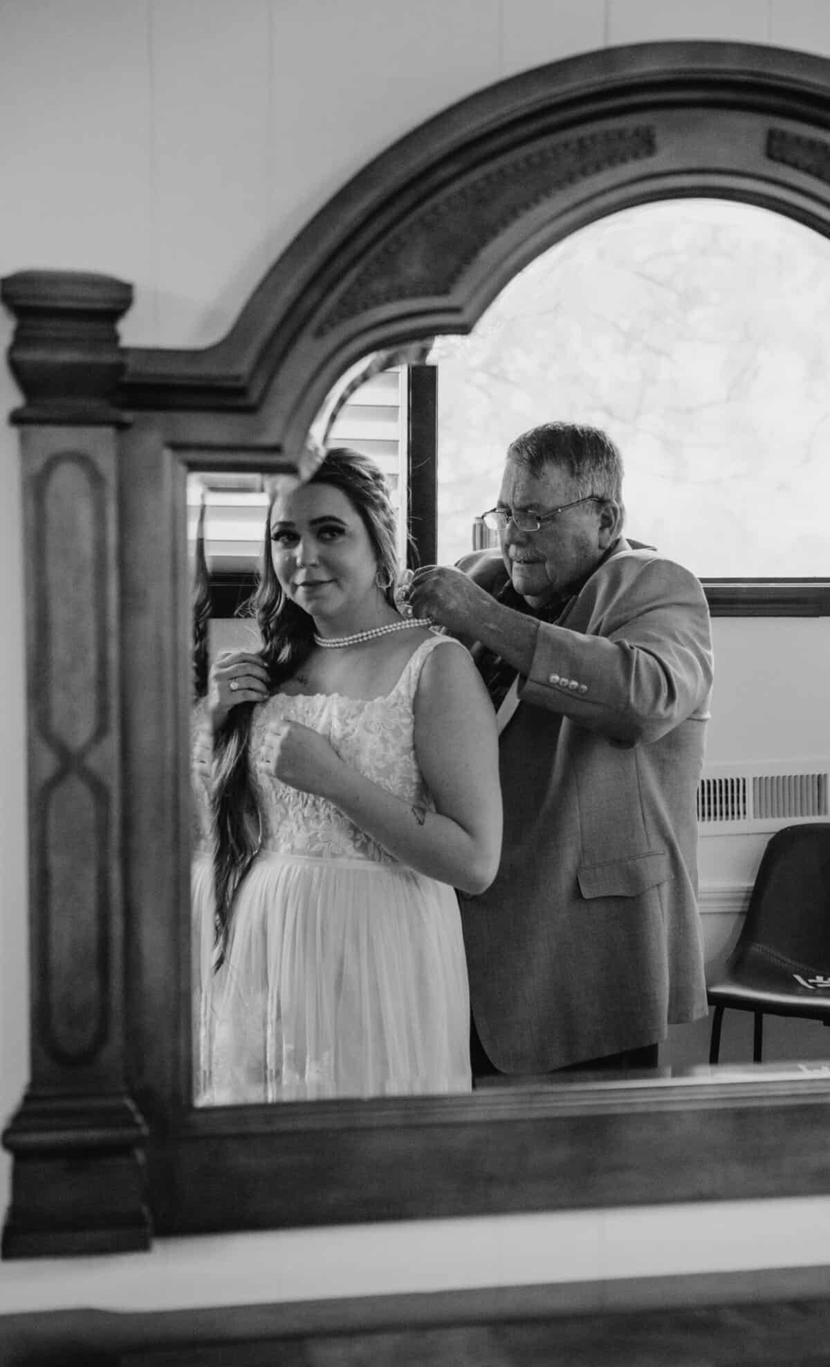 Papa putting a pearl necklace on the bride.