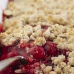 Serving cherry cobbler with a cake mix with a spoon.
