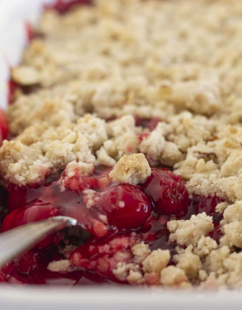 Serving cherry cobbler with a cake mix with a spoon.
