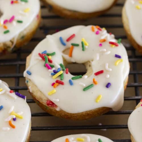 Funfetti donuts on a wire rack with vanilla glaze.