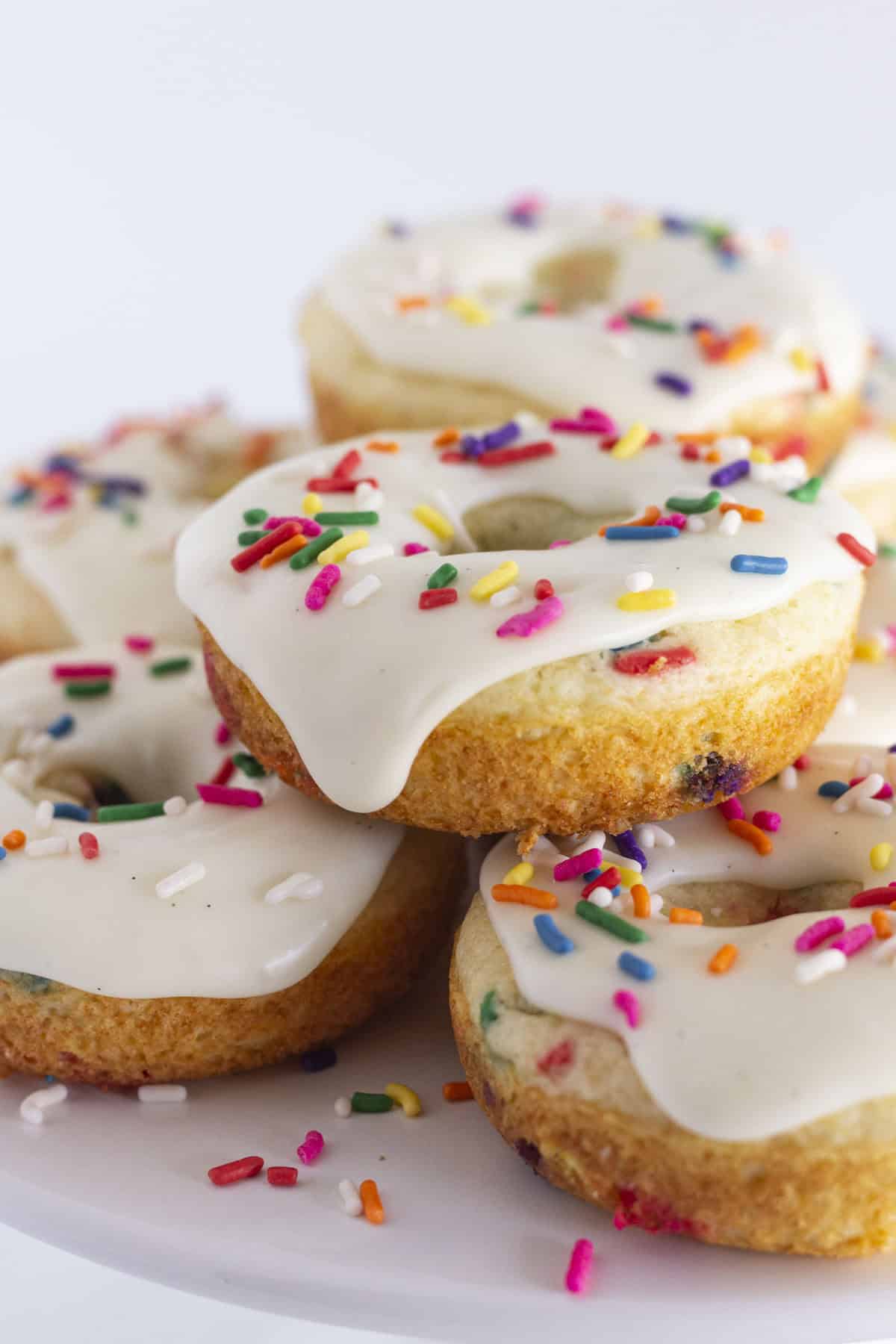 Funfetti donuts on a white cake plate for serving.