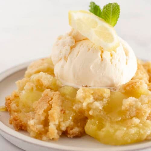 A serving of lemon dump cake on a plate with vanilla ice cream.