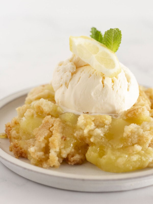 A serving of lemon dump cake on a plate with vanilla ice cream.