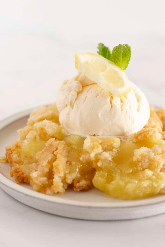 A serving of lemon dump cake on a plate with vanilla ice cream.