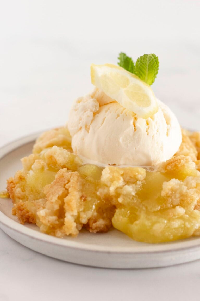 A serving of lemon dump cake on a plate with vanilla ice cream.