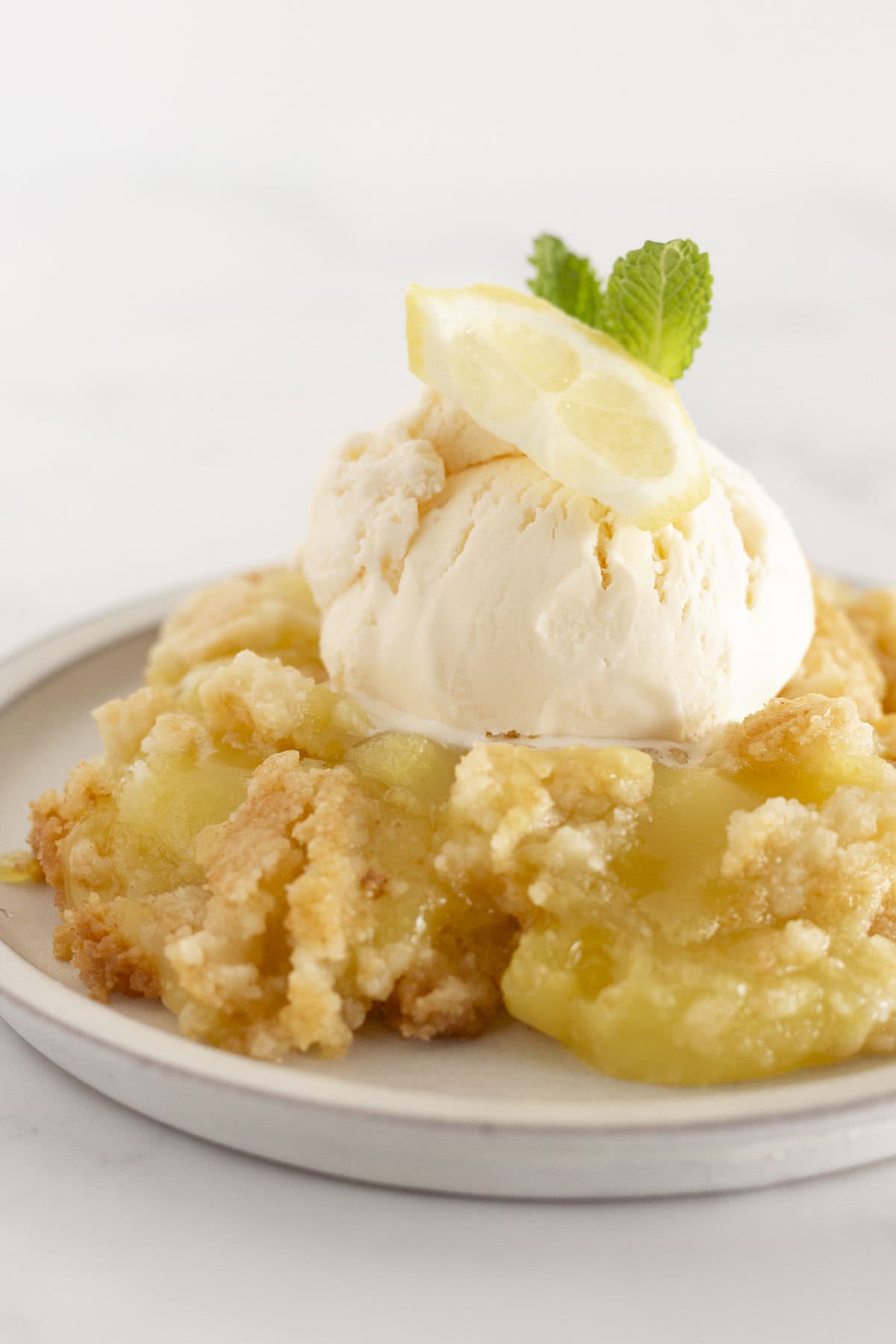 A serving of lemon dump cake with a couple scoops of vanilla ice cream on top.