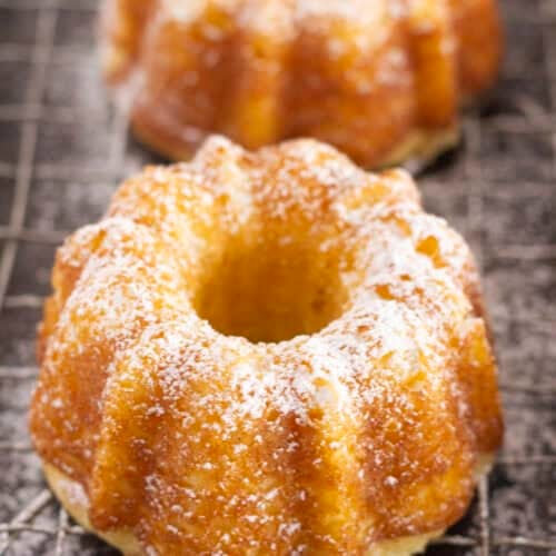 Mini pound cakes on a cooling rack with a sprinkle of powdered sugar.