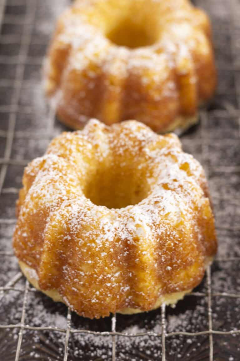 Mini pound cakes on a cooling rack with a sprinkle of powdered sugar.