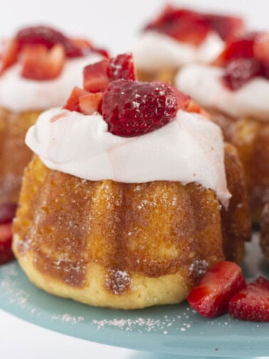 Mini strawberry shortcakes on a tray with a sprinkle of powdered sugar.