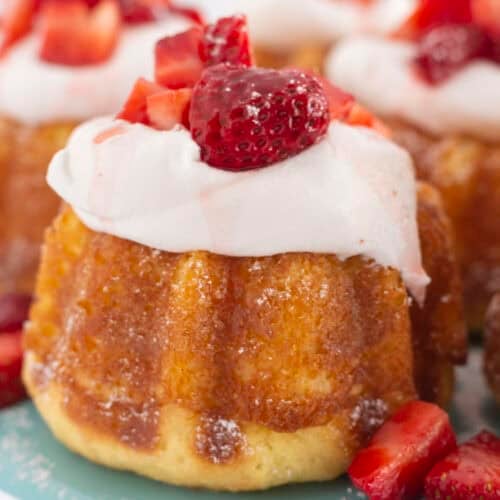 Mini strawberry shortcakes on a tray with a sprinkle of powdered sugar.