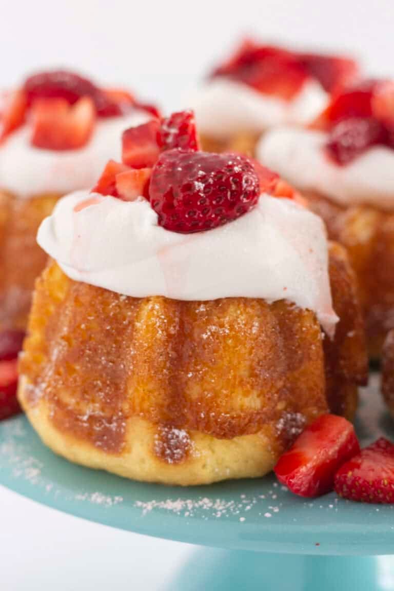 Mini strawberry shortcakes on a tray with a sprinkle of powdered sugar.