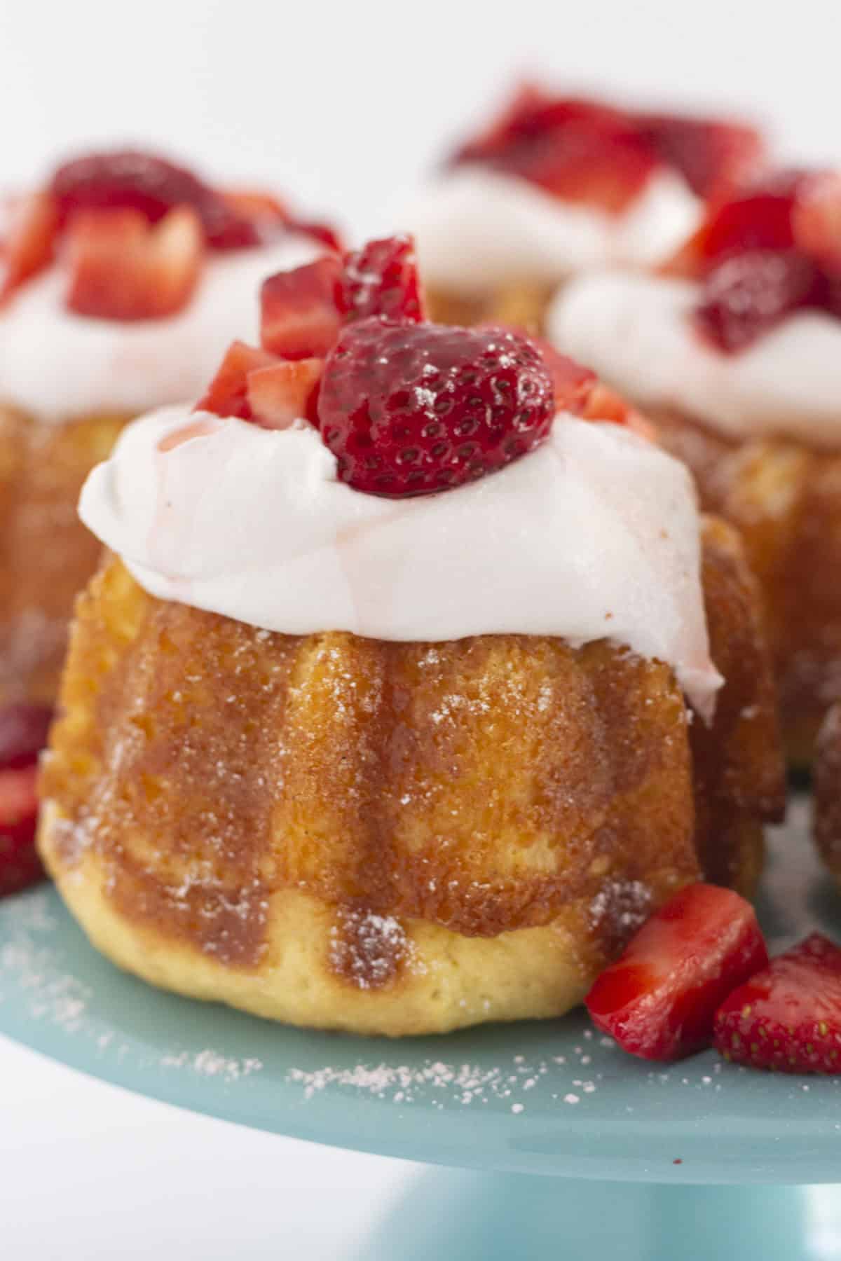 Mini strawberry shortcakes on a tray with a sprinkle of powdered sugar.