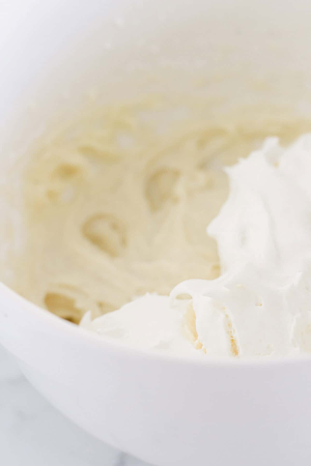 Making the cream cheese frosting in a white bowl.