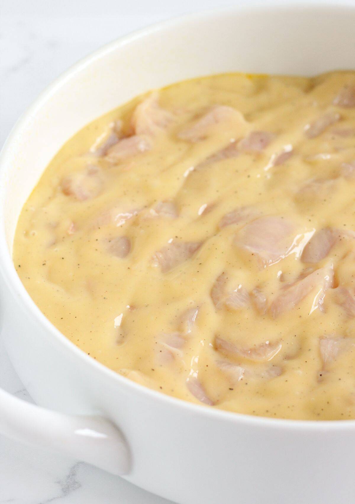 Combining the chicken and sauce, then pouring in a casserole dish.