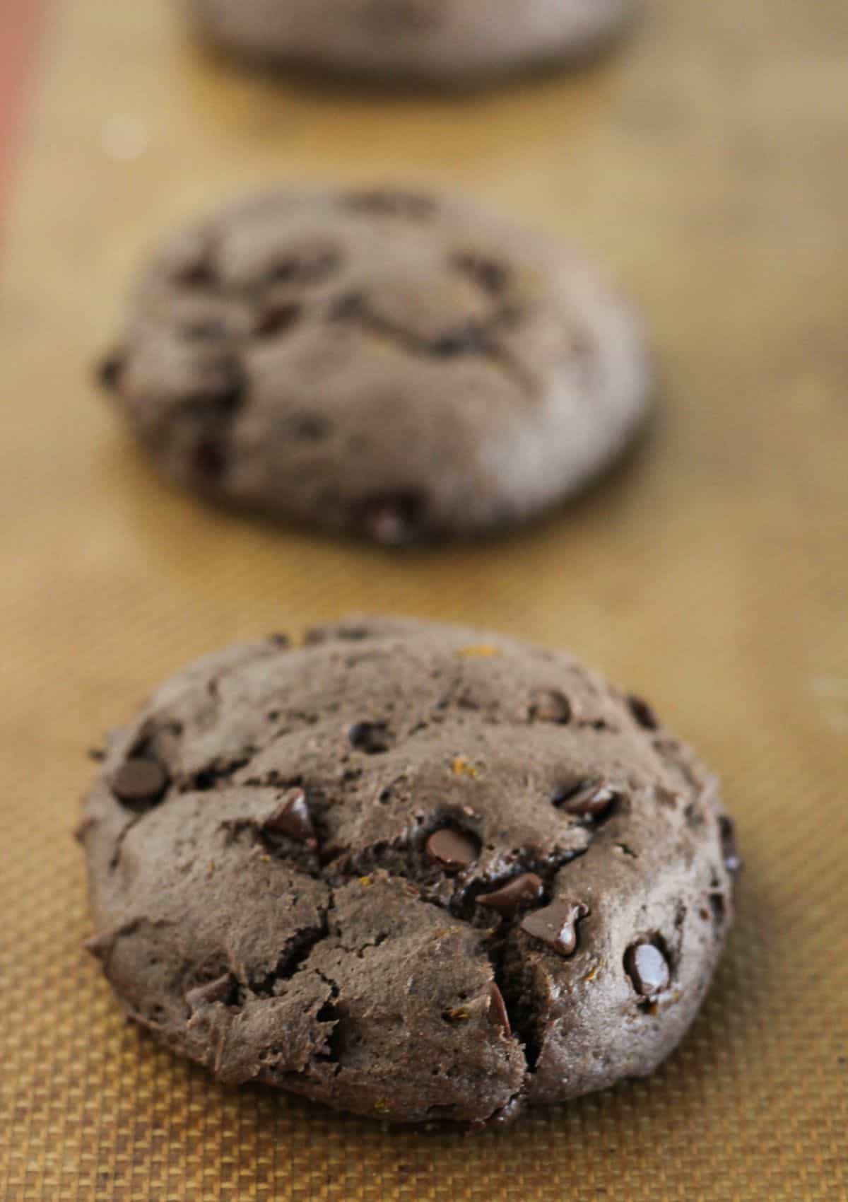 Baked chocolate orange cookies on baking sheet cooling.