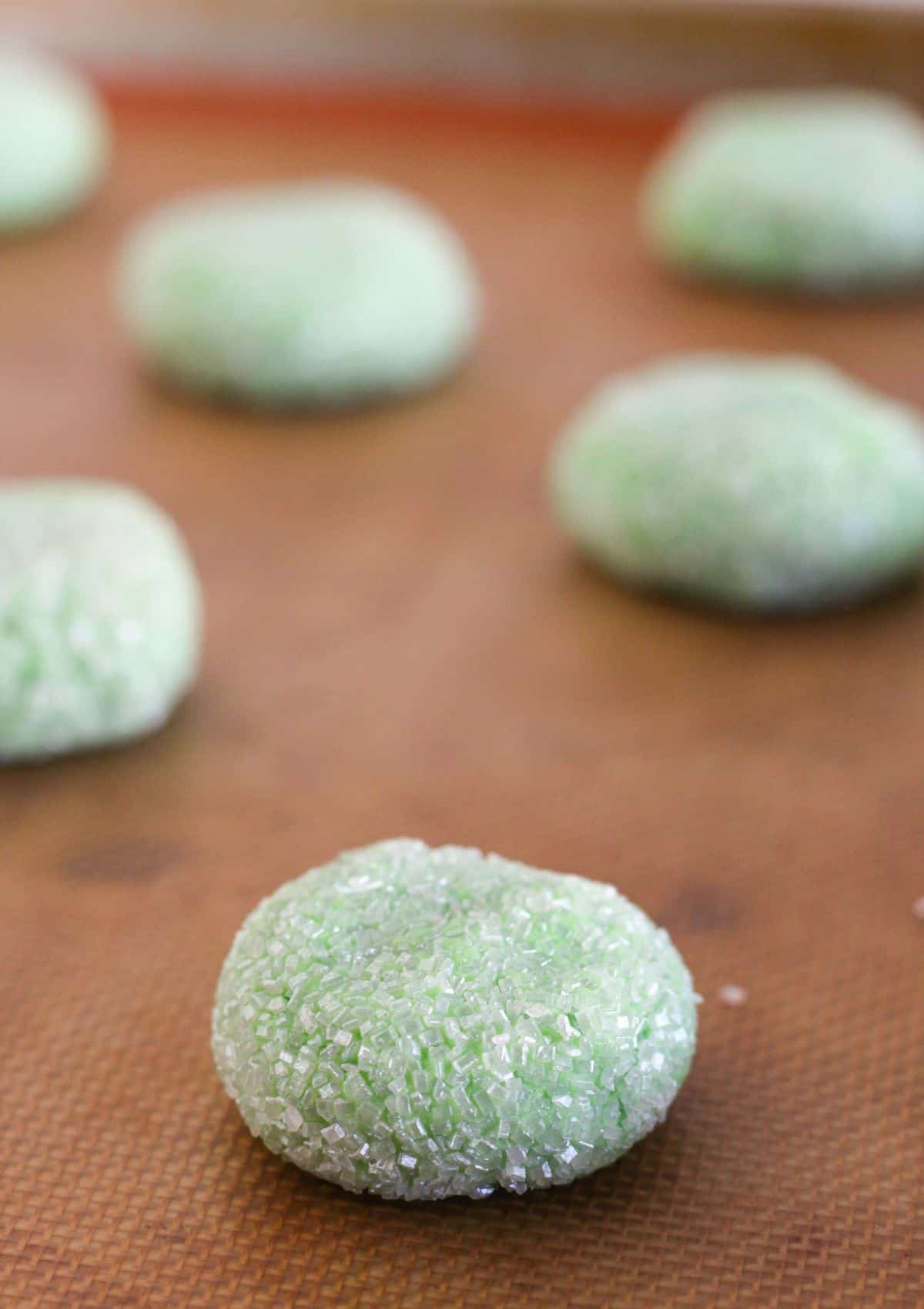 Adding the sugar coated cookie dough onto a baking sheet.