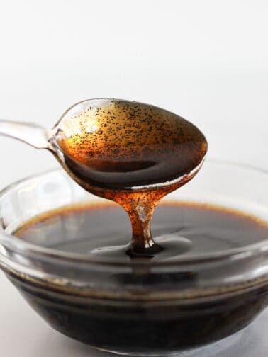 Vanilla bean paste in a clear bowl with a spoon.