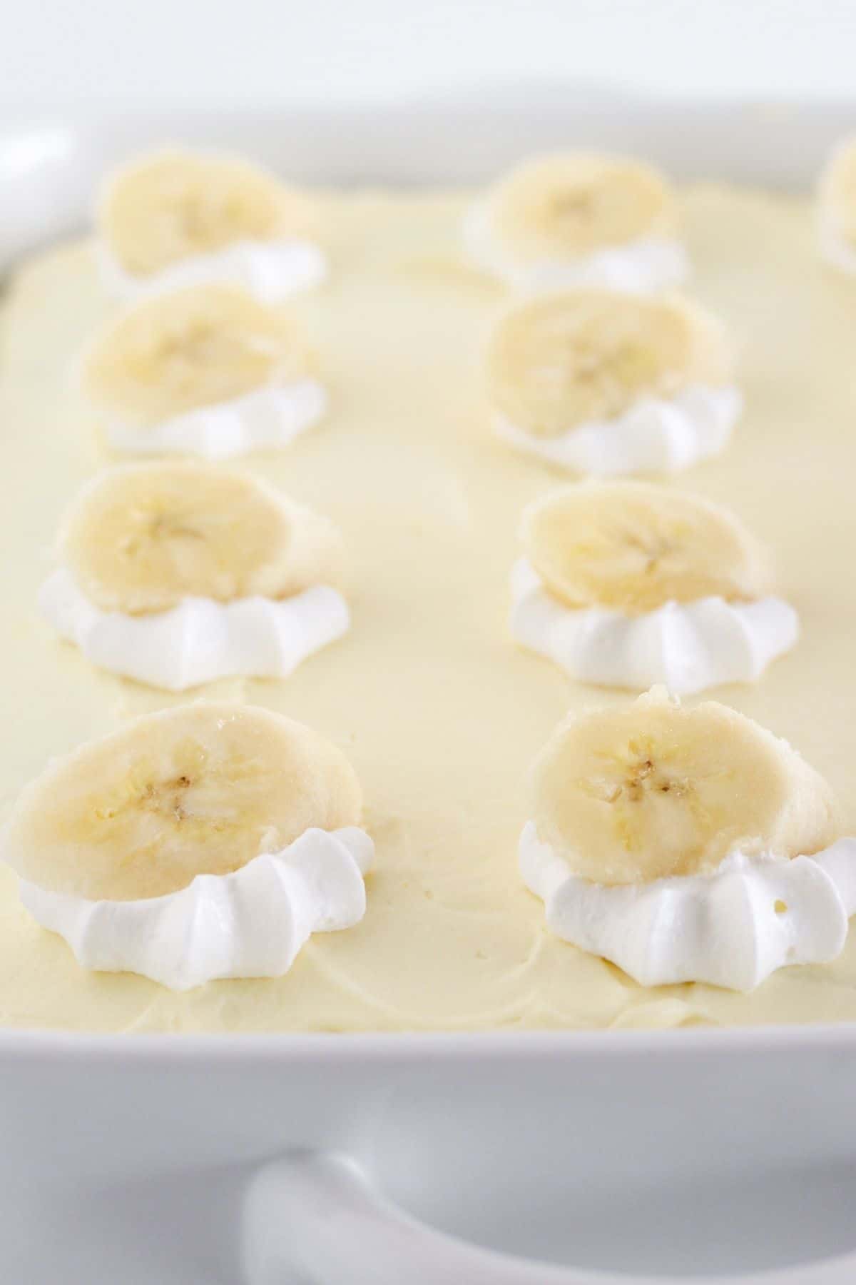 A frosted banana sheet cake with fresh banana slices.