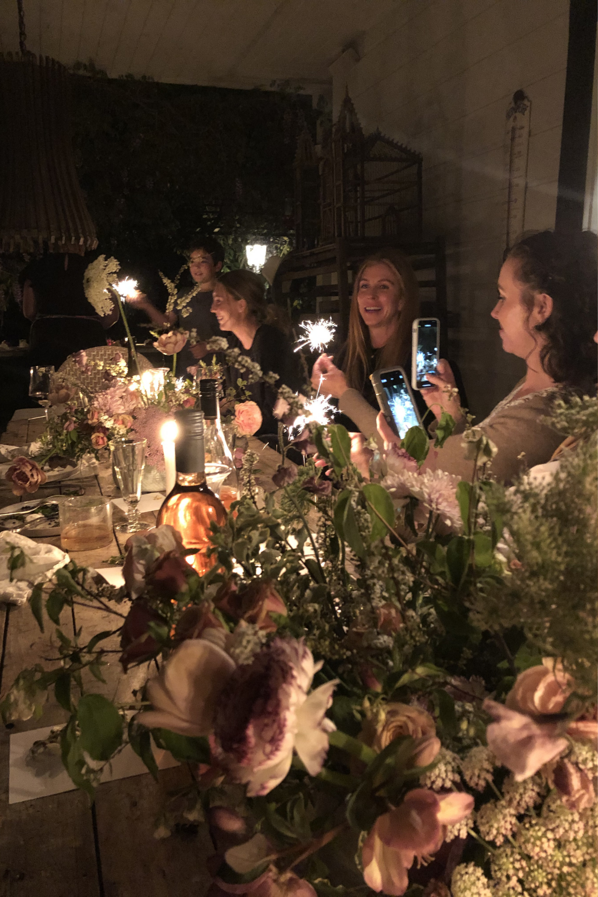 A dinner party in the dark at a candle lit table.