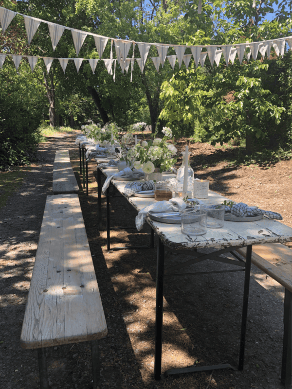 A wooden table and benches set up for dinner in the trees.