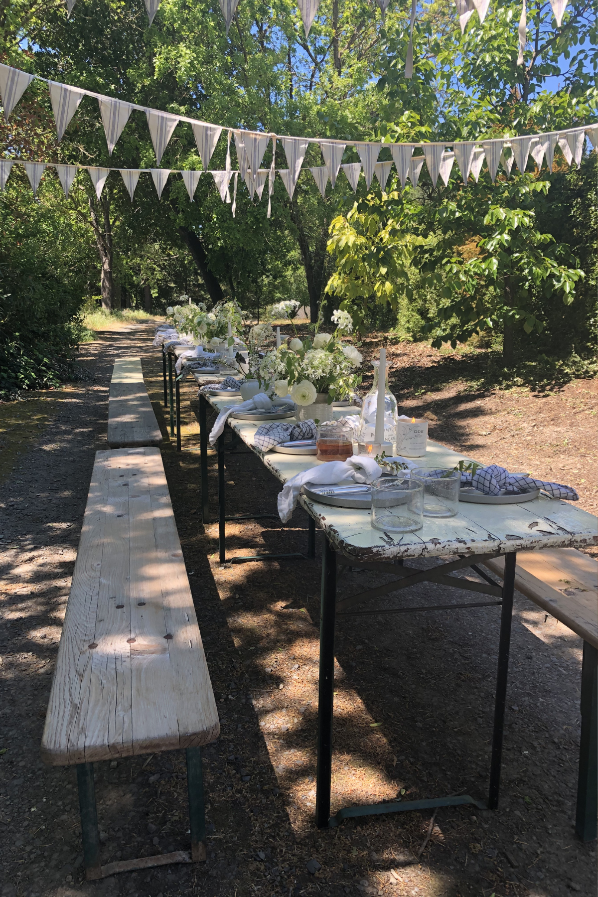 A wooden table and benches set up for dinner in the trees.