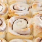 Close up of frosted cinnamon rolls in pan.