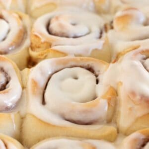 Close up of frosted cinnamon rolls in pan.