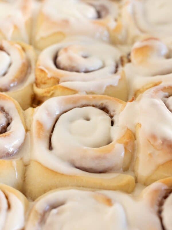 Close up of frosted cinnamon rolls in pan.
