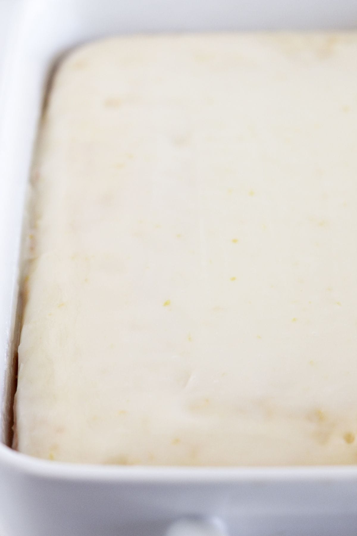 Pouring the frosting on a lemon cake.