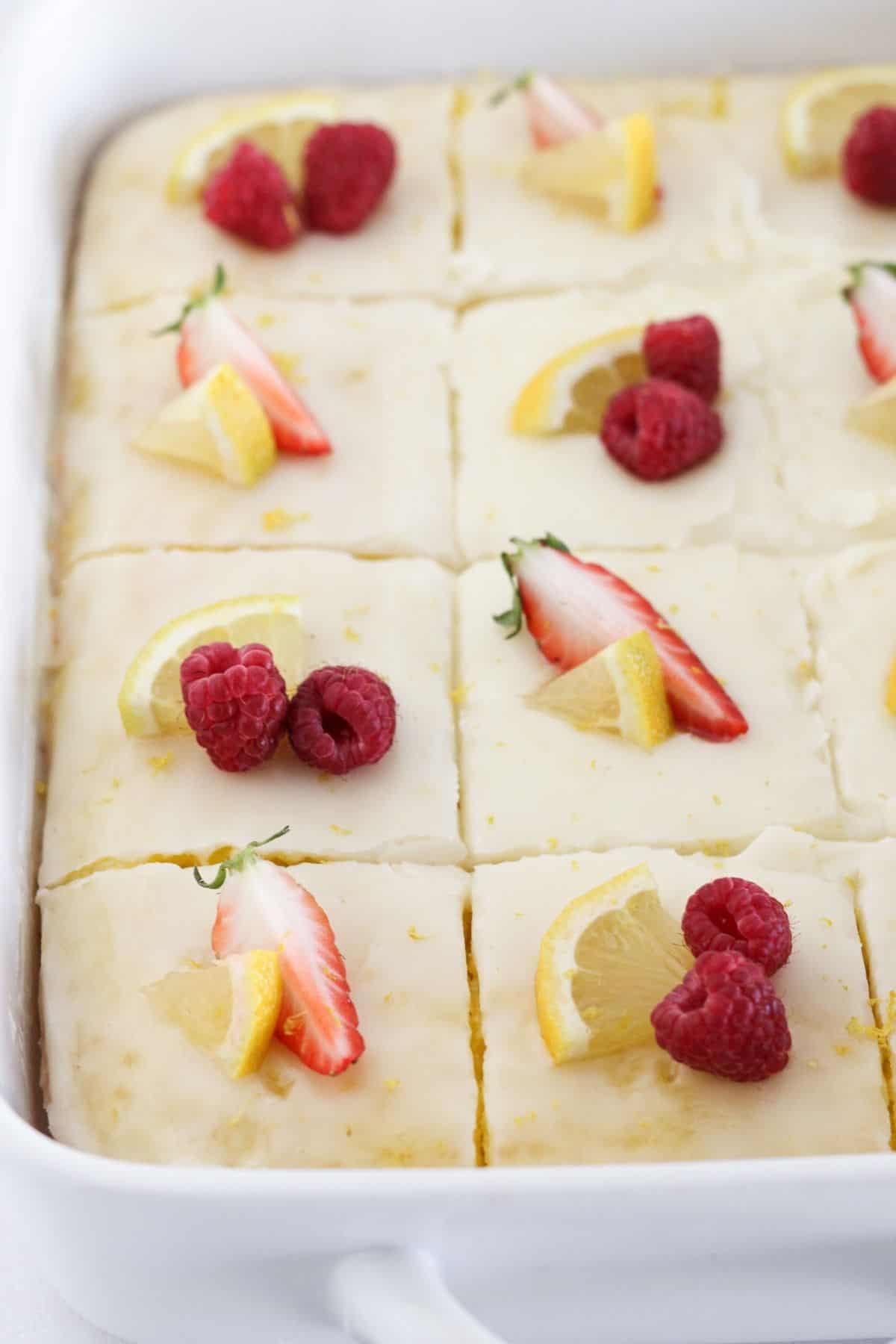 A finished lemon cake in a sheet pan with fresh fruit.
