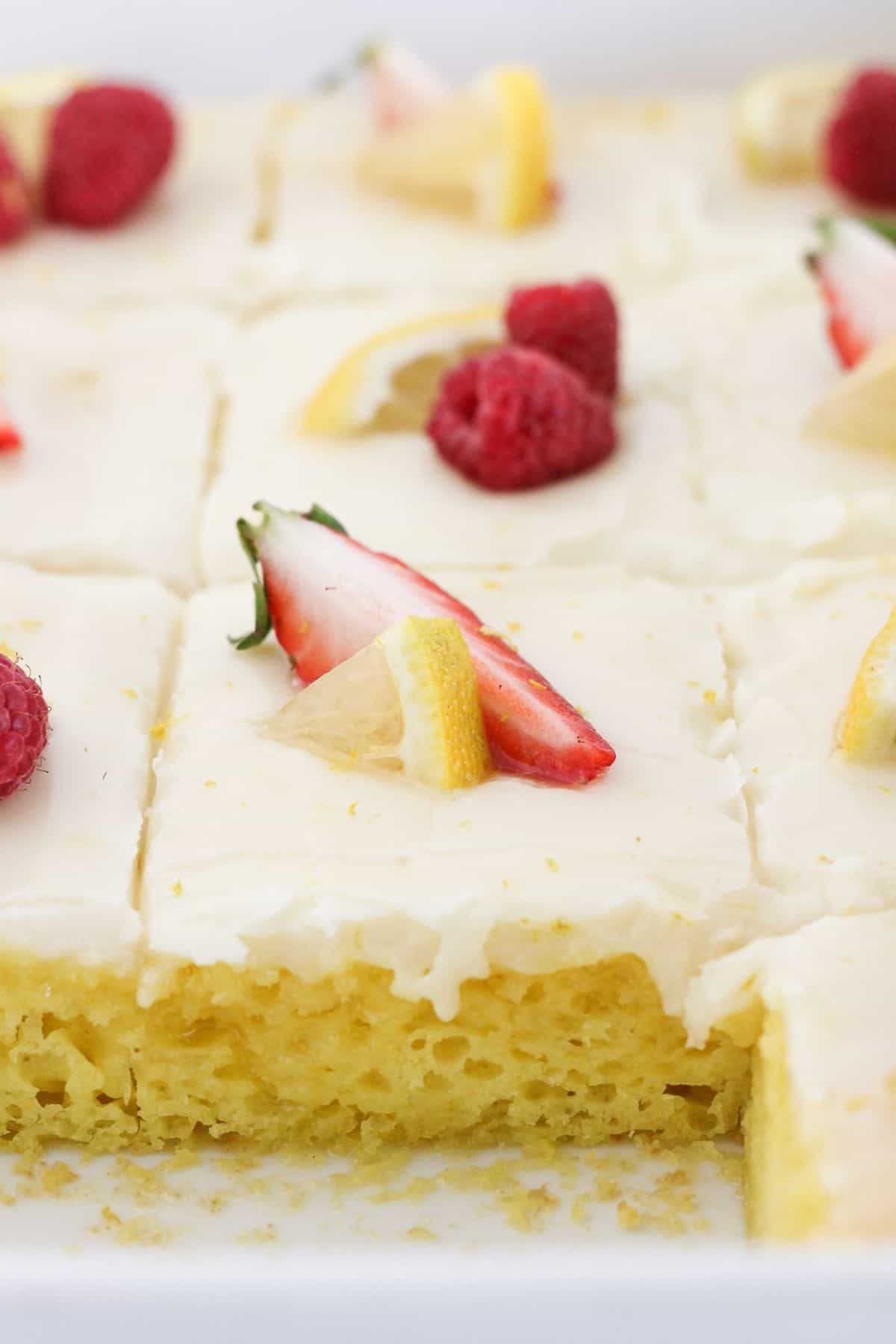 A lemon sheet cake with a few pieces missing.