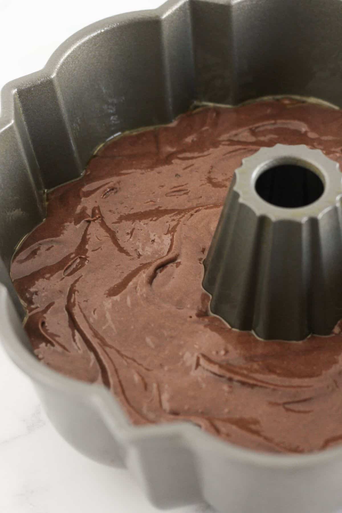 Adding the cake batter to a prepared bundt pan.