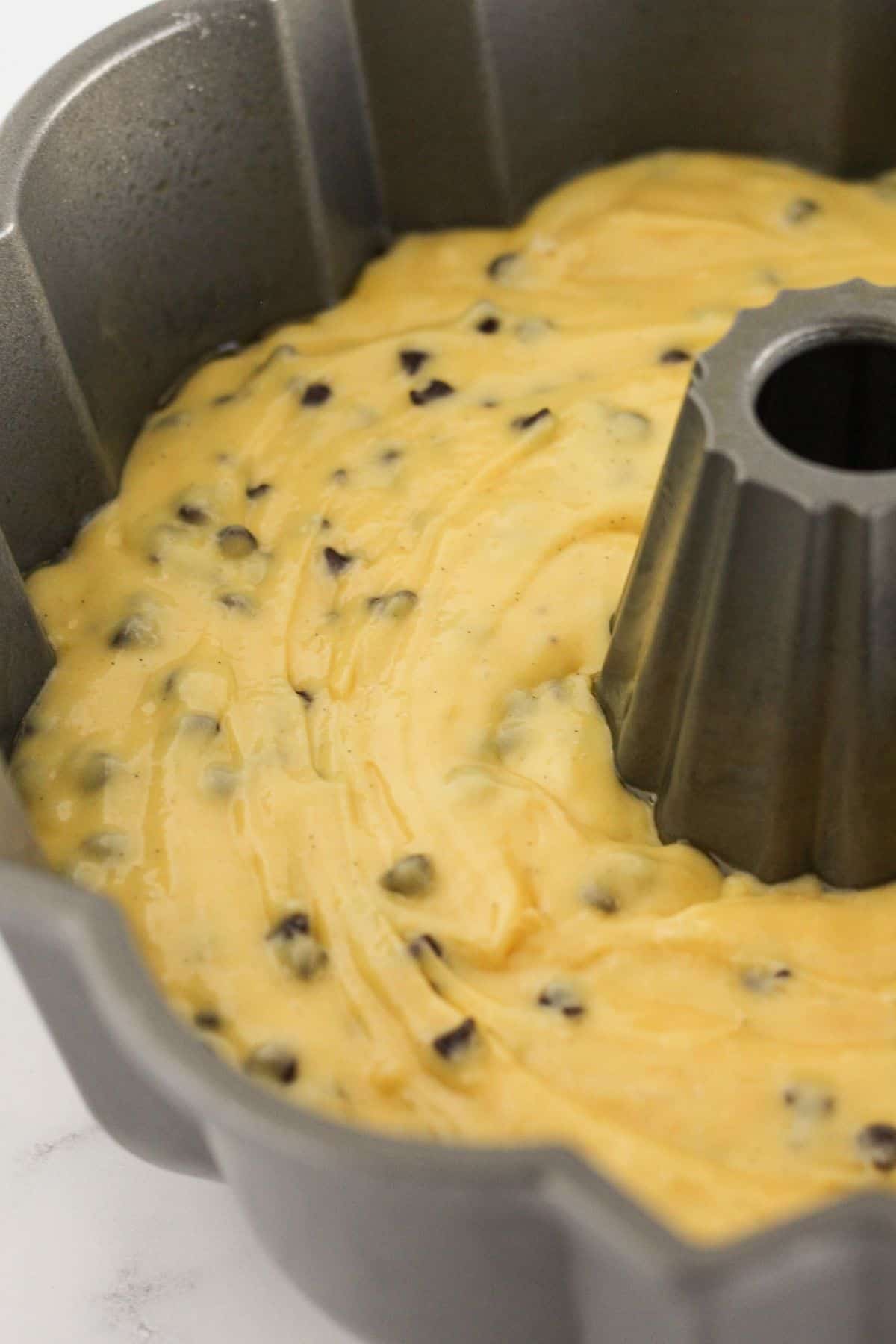 Cake batter in a bundt pan with chocolate chips.