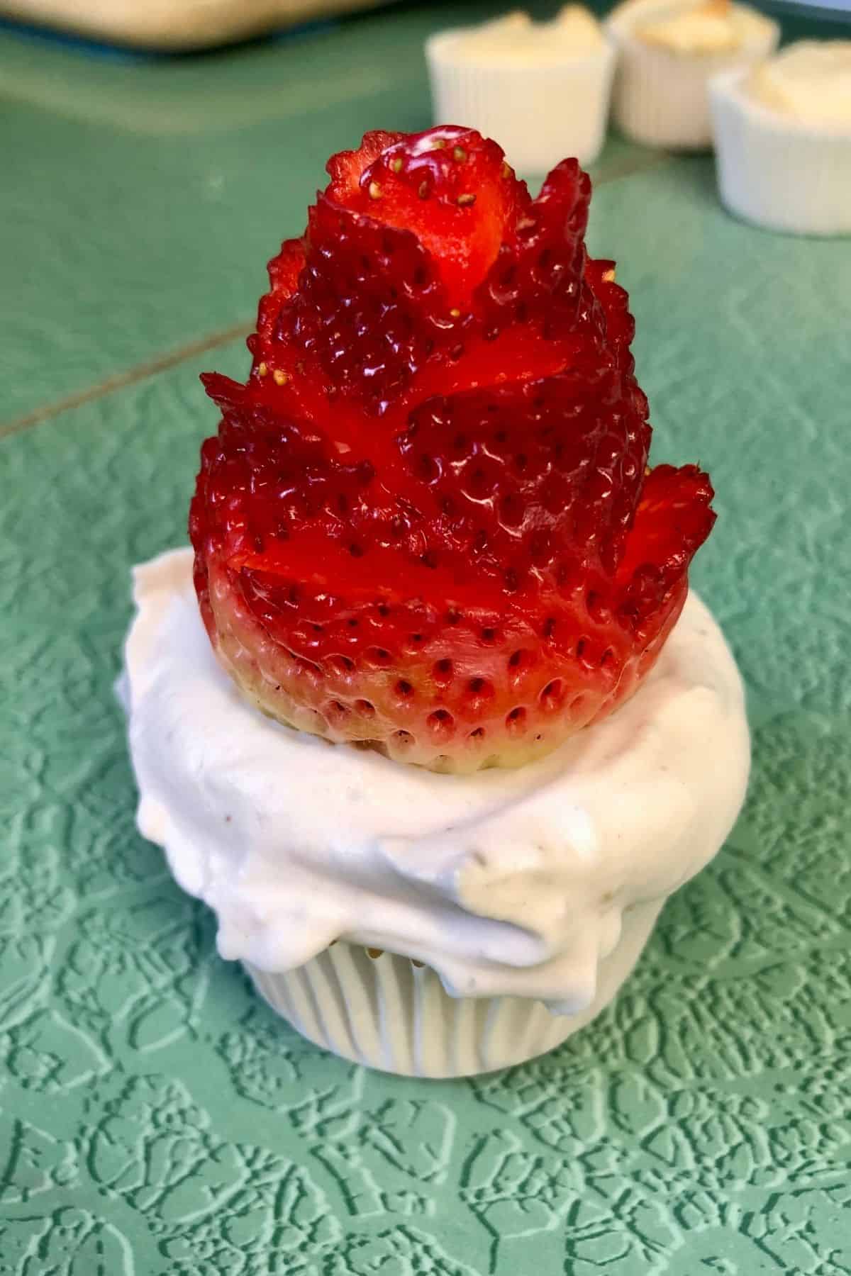 A cupcake with a strawberry rose on top.