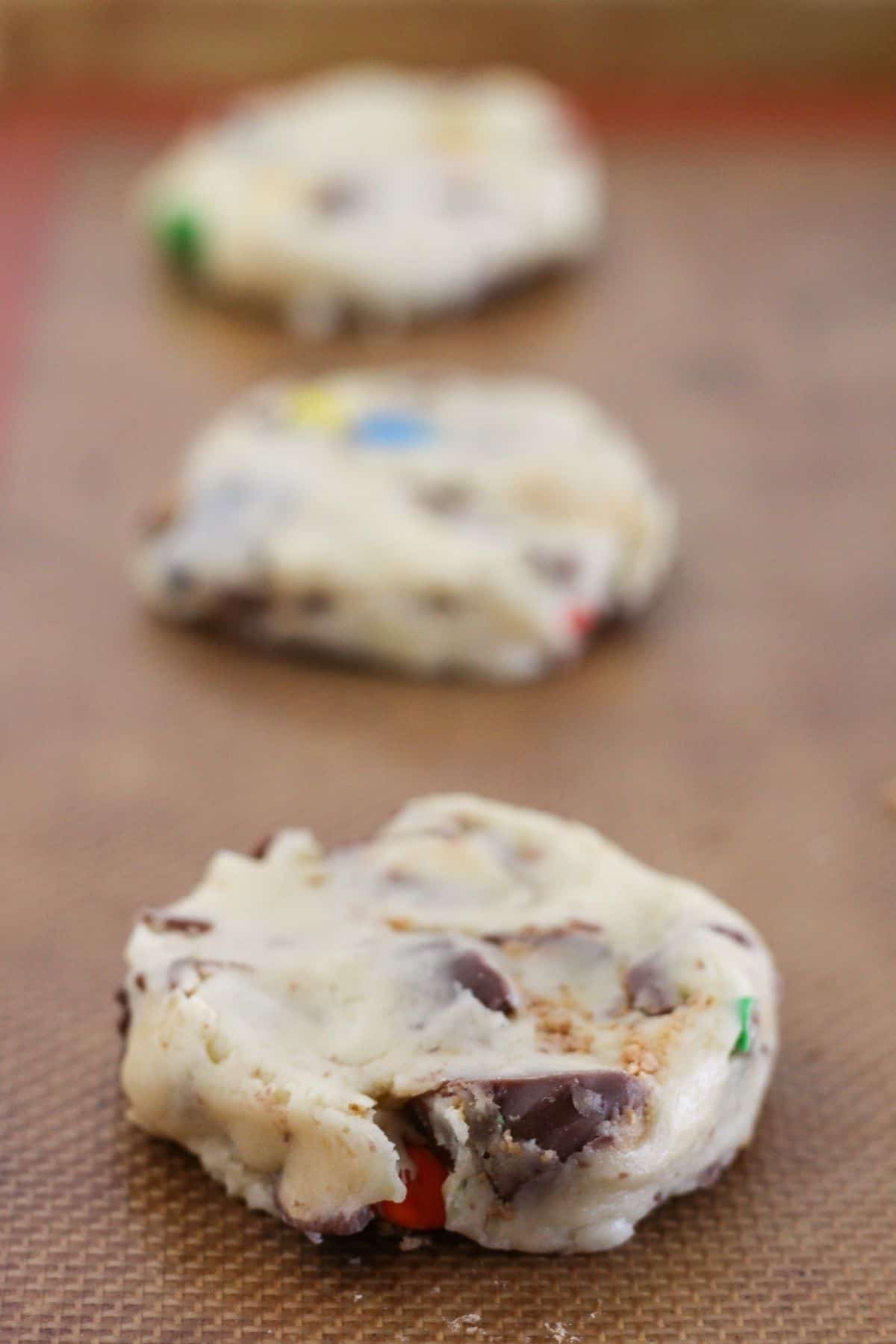 Halloween candy cookie dough discs on a sheet pan.